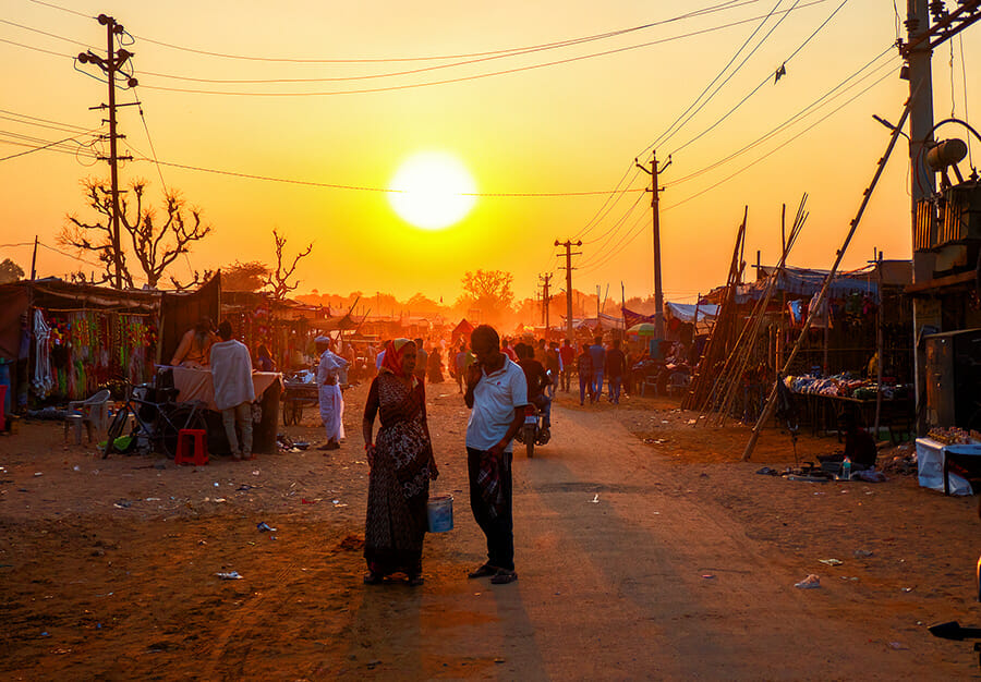 sunset on Pushkar Festival and people standing between the stalls